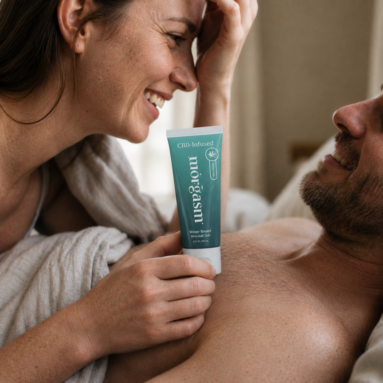 Couple in bed holding the CBD-Infused tube